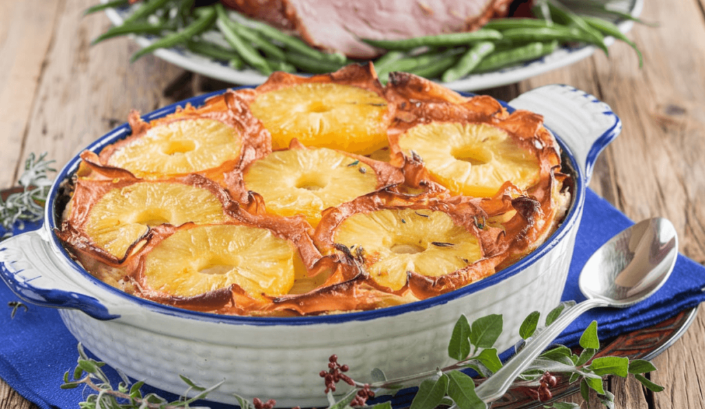 A beautifully baked pineapple casserole topped with golden pineapple rings in a white dish.