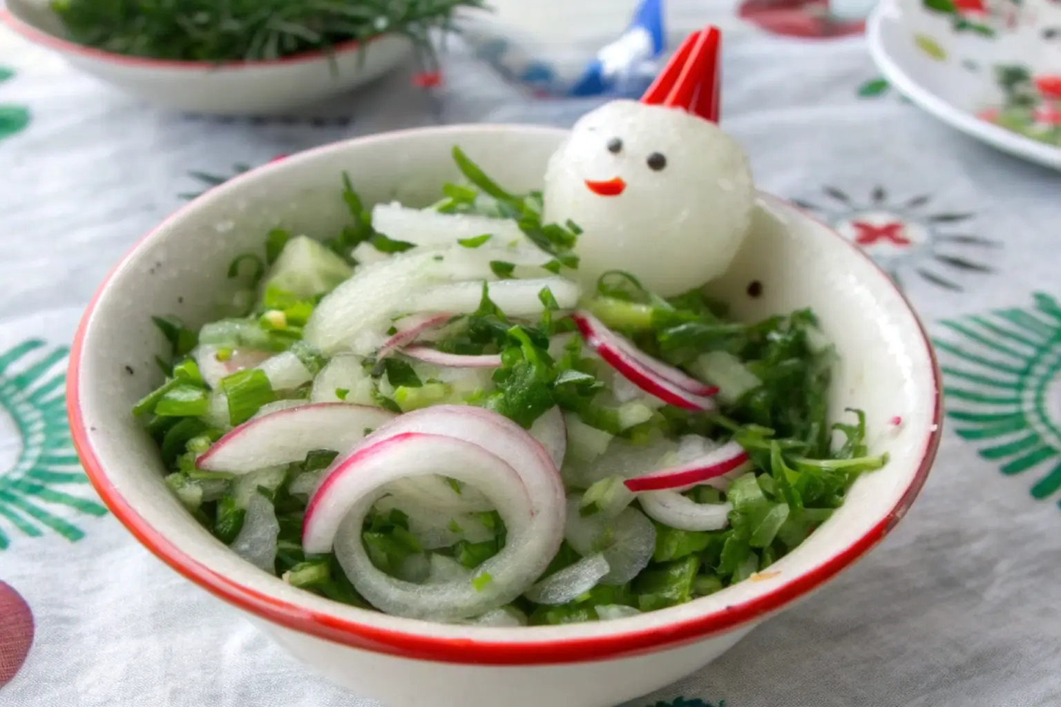 Fresh onion salad with chopped greens and a playful boiled egg decoration in a festive bowl.