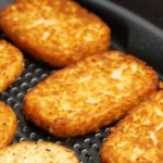 Crispy golden hash brown patties in an air fryer tray.